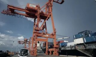 Ship-to-shore cranes over stacked containers at a port terminal.